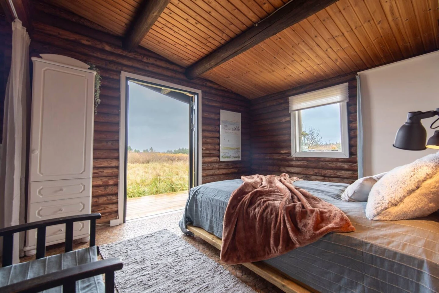 Schlafzimmer mit offener Tür zur Terrasse und Blick ins Grüne
