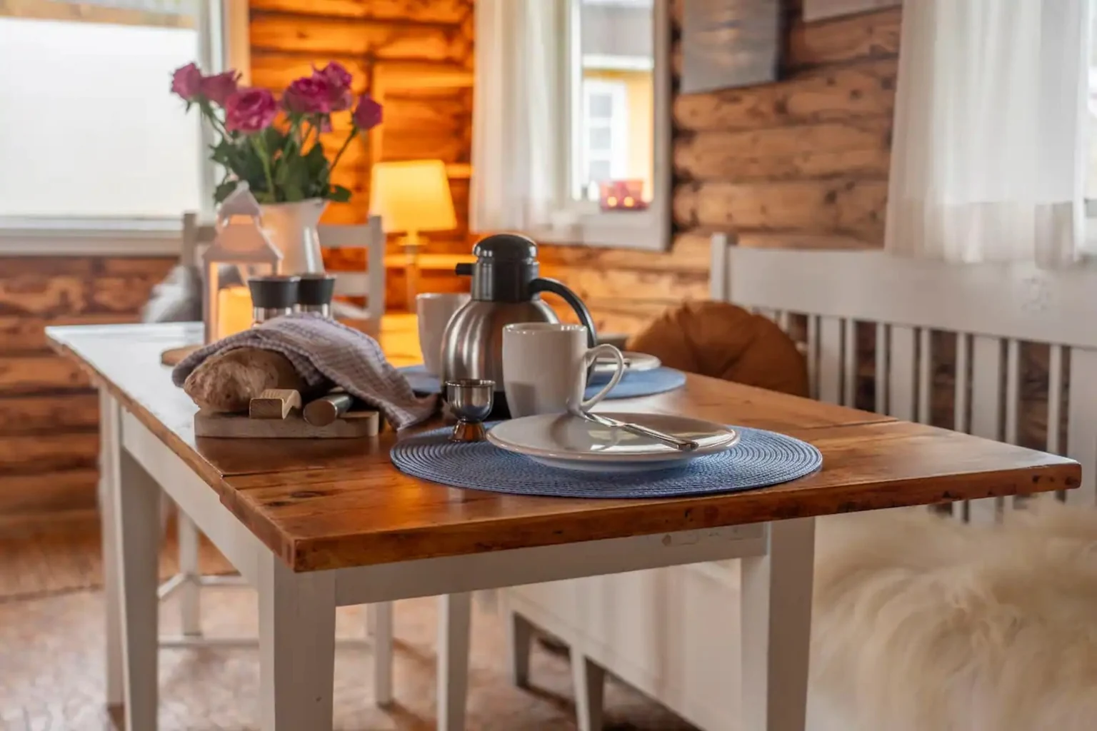 Gedeckter Tisch mit Kaffeekanne und Blumen