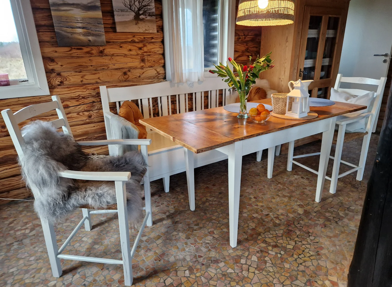 Esstisch aus Holz mit weißen Stühlen und Blumen