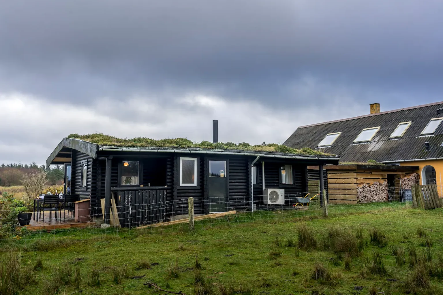 Das Blockhaus mit Gründach neben dem gelben Wohnhaus des Hofs