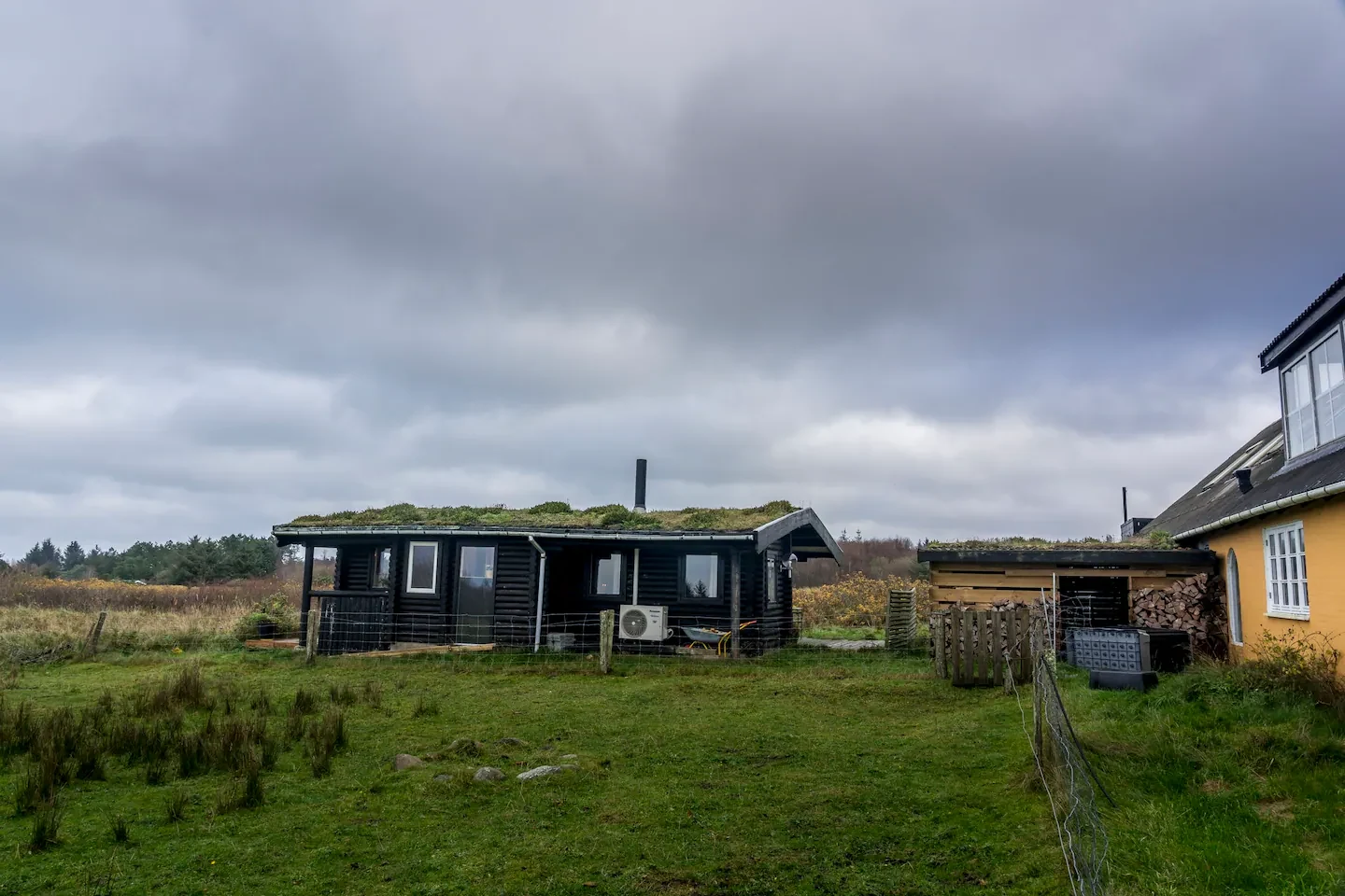 Blick über die Weide auf das Blockhaus mit Gründach