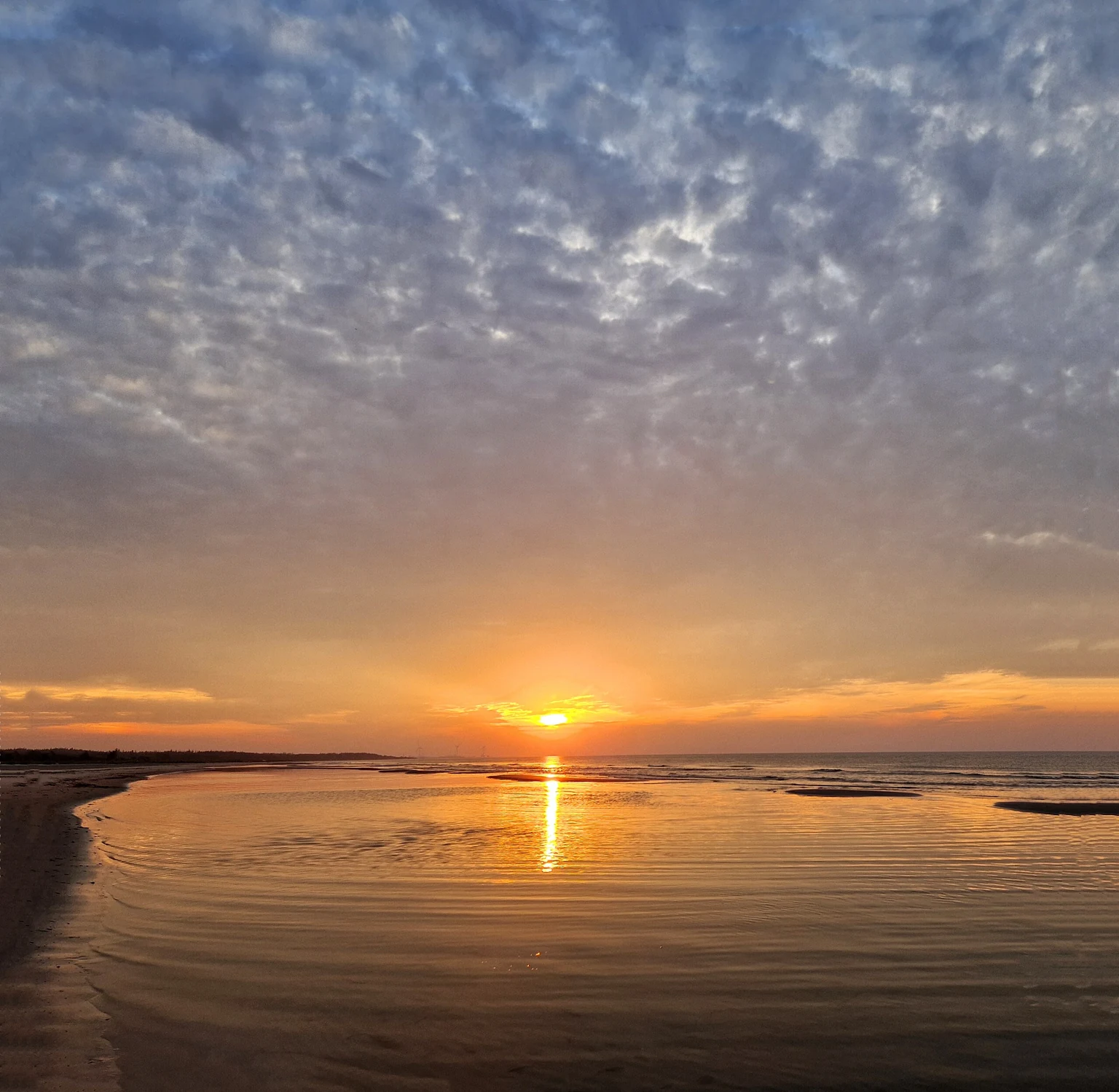 Sonnenuntergang über dem Meer, die Sonne spiegelt sich im flachen Wasser