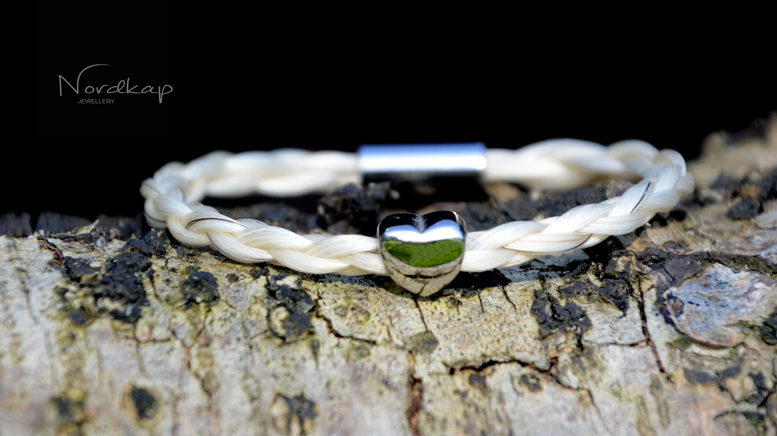 Armband aus hellem, geflochtenem Pferdehaar mit silberfarbenem Herz auf Birkenrinde
