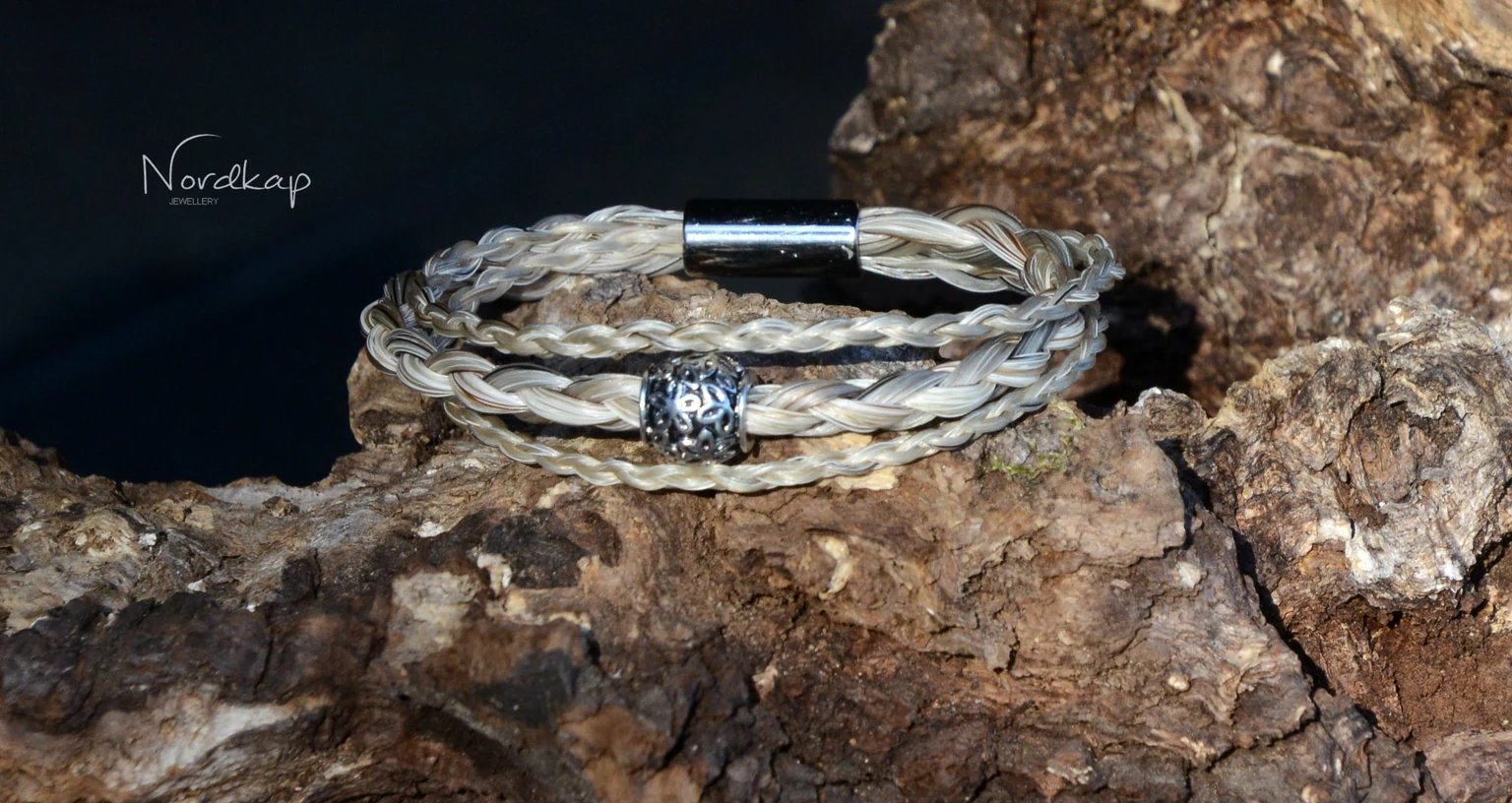 Armband aus drei Strängen grauem und hellem Pferdehaar auf einem Stein